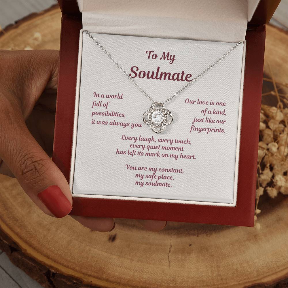 Handheld view of love knot necklace in gift box featuring soulmate message In a world full of possibilities.