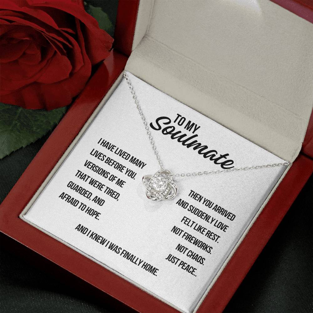 Angled view of white gold soulmate love knot necklace on white background with message about guarded hearts and peaceful love