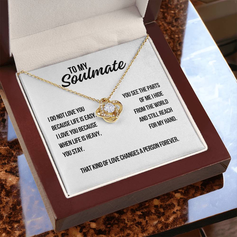 Lifestyle photo of yellow gold soulmate love knot necklace on white background with message about standing by each other when life is heavy